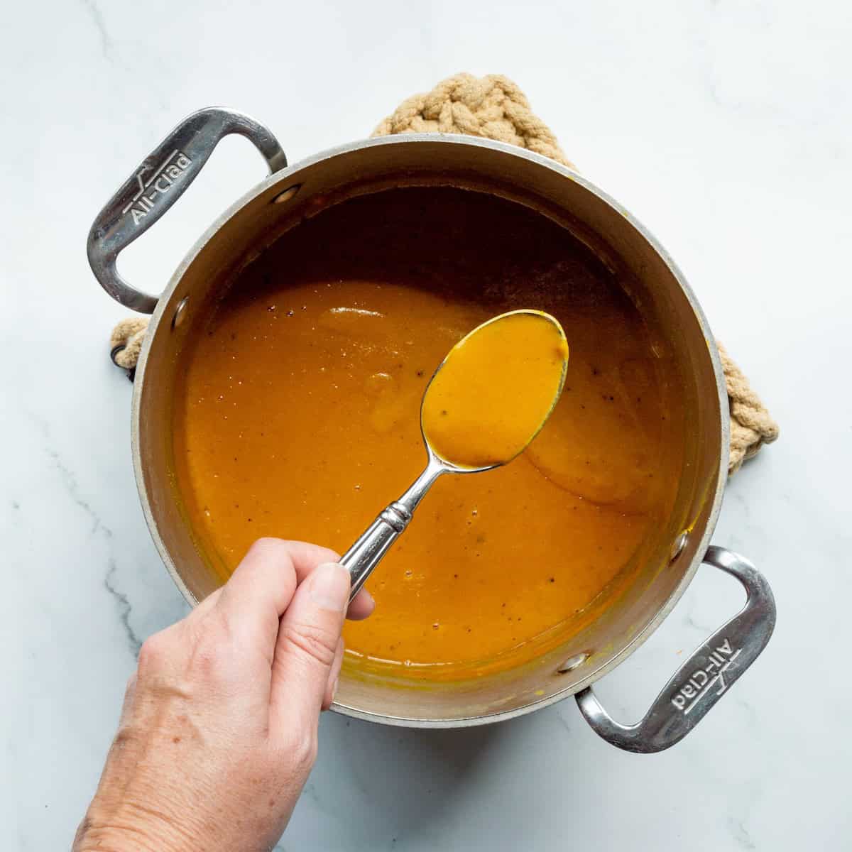 Lifting thickened Carolina Gold BBQ Sauce in a spoon.
