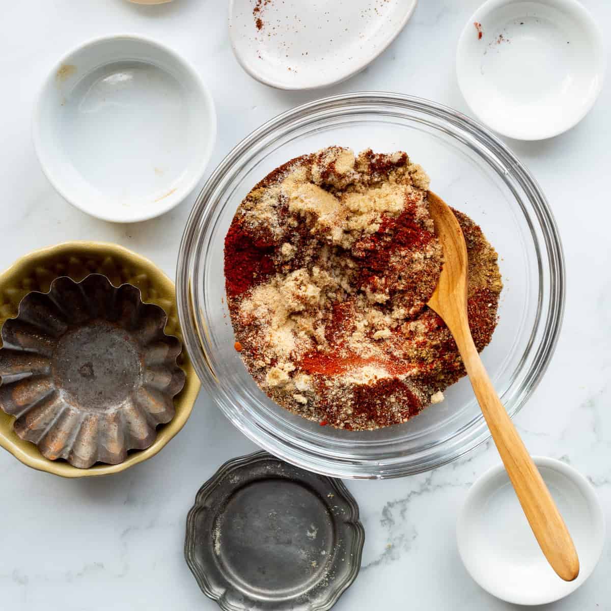 Stirring together the ingredients for Desert Heat Dry Rub in a glass bowl with small dishes surrounding the bowl.