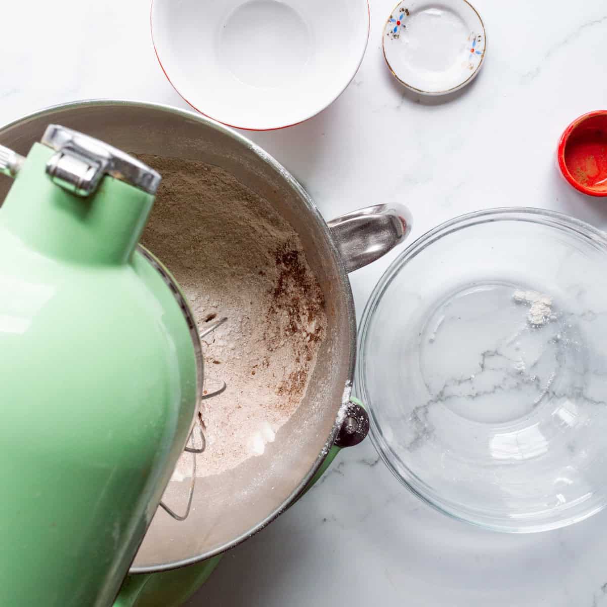 Mixing the dry ingredients together for red velvet cake in a green KitchenAid mixer.