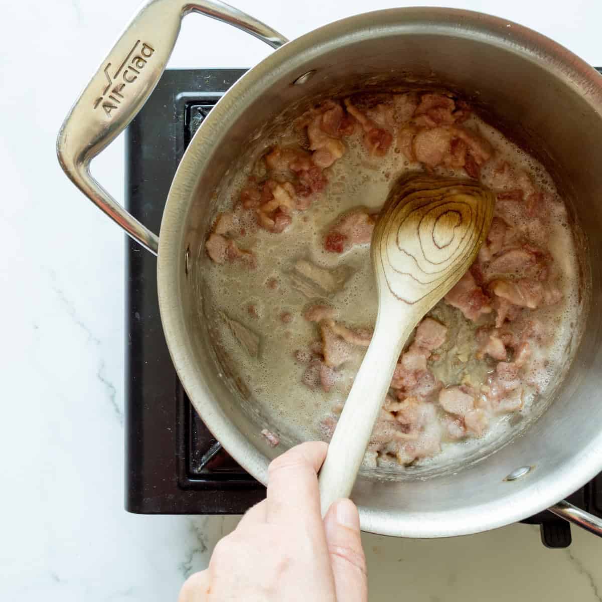 Cooking chopped bacon in a large saucepan.