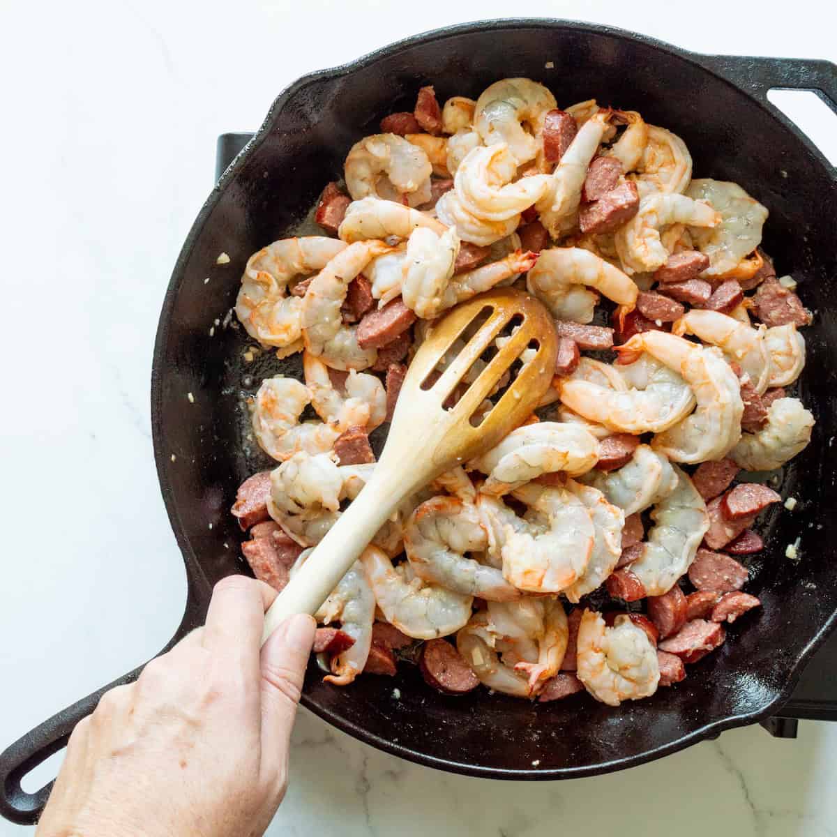 Sautéing shrimp and sausage in a cast-iron skillet.