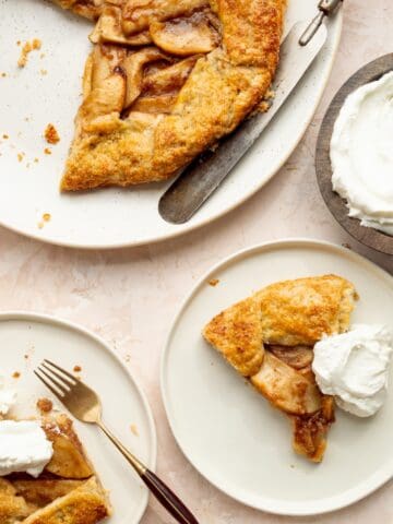 Copycat Maggiano's Apple Crostata on a round platter with a wooden handled serving knife, bowl of whipped cream, and servings of crostata on plates.