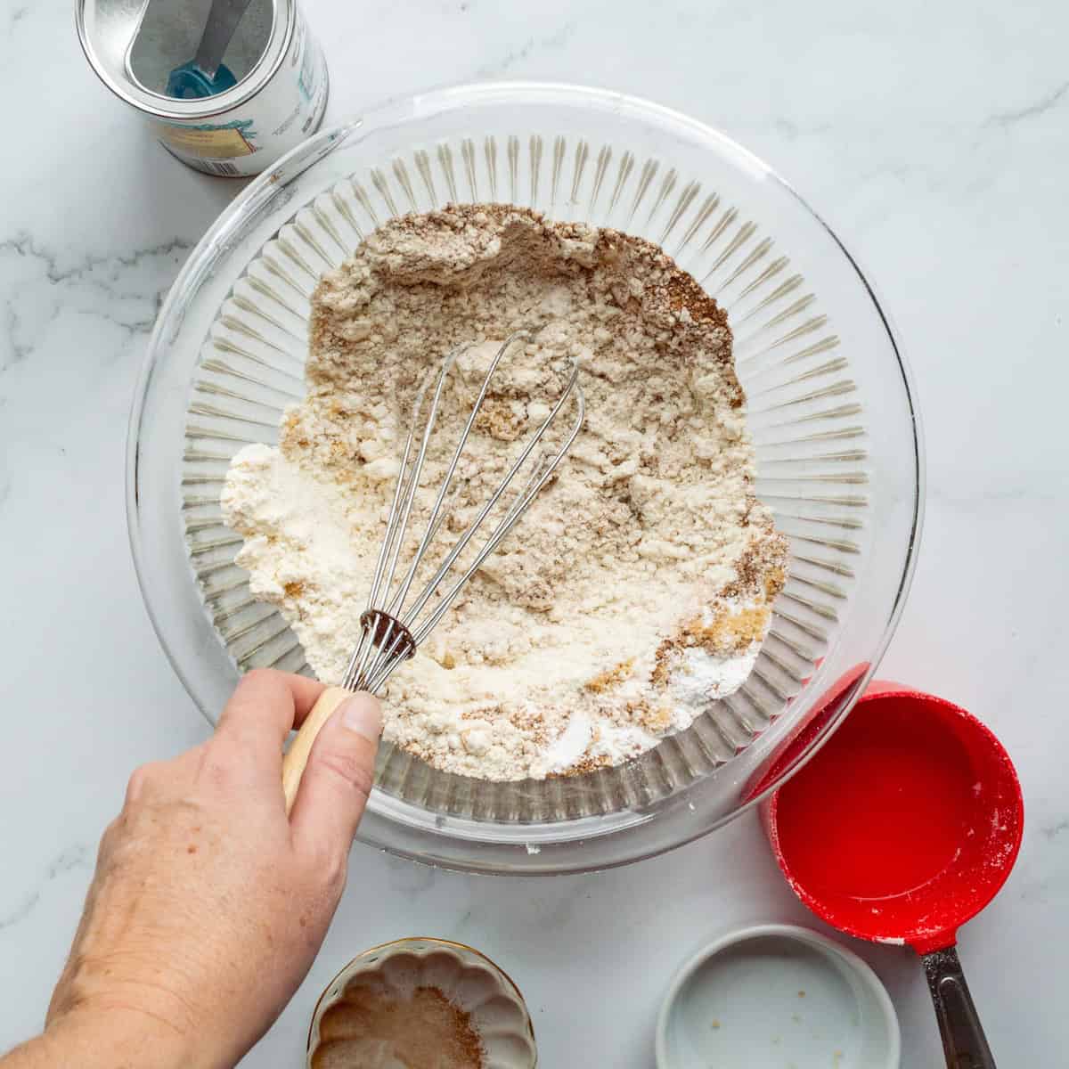 Mixing the dry ingredients for pumpkin pancakes in a clear glass bowl.