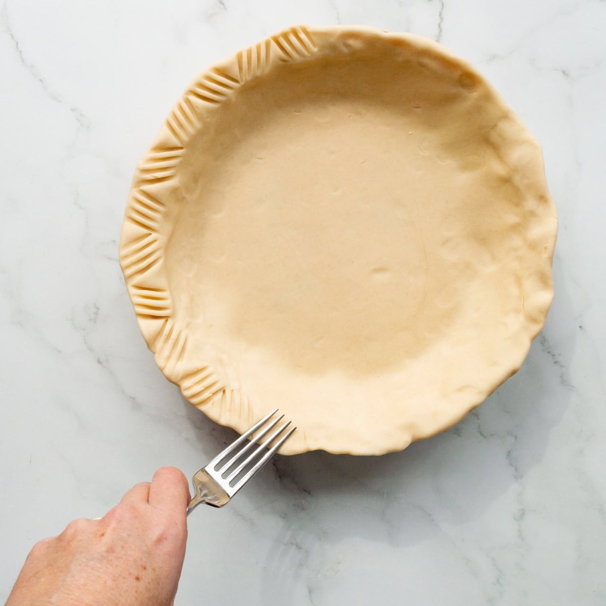 Crimping the edge of a pie crust with a fork.
