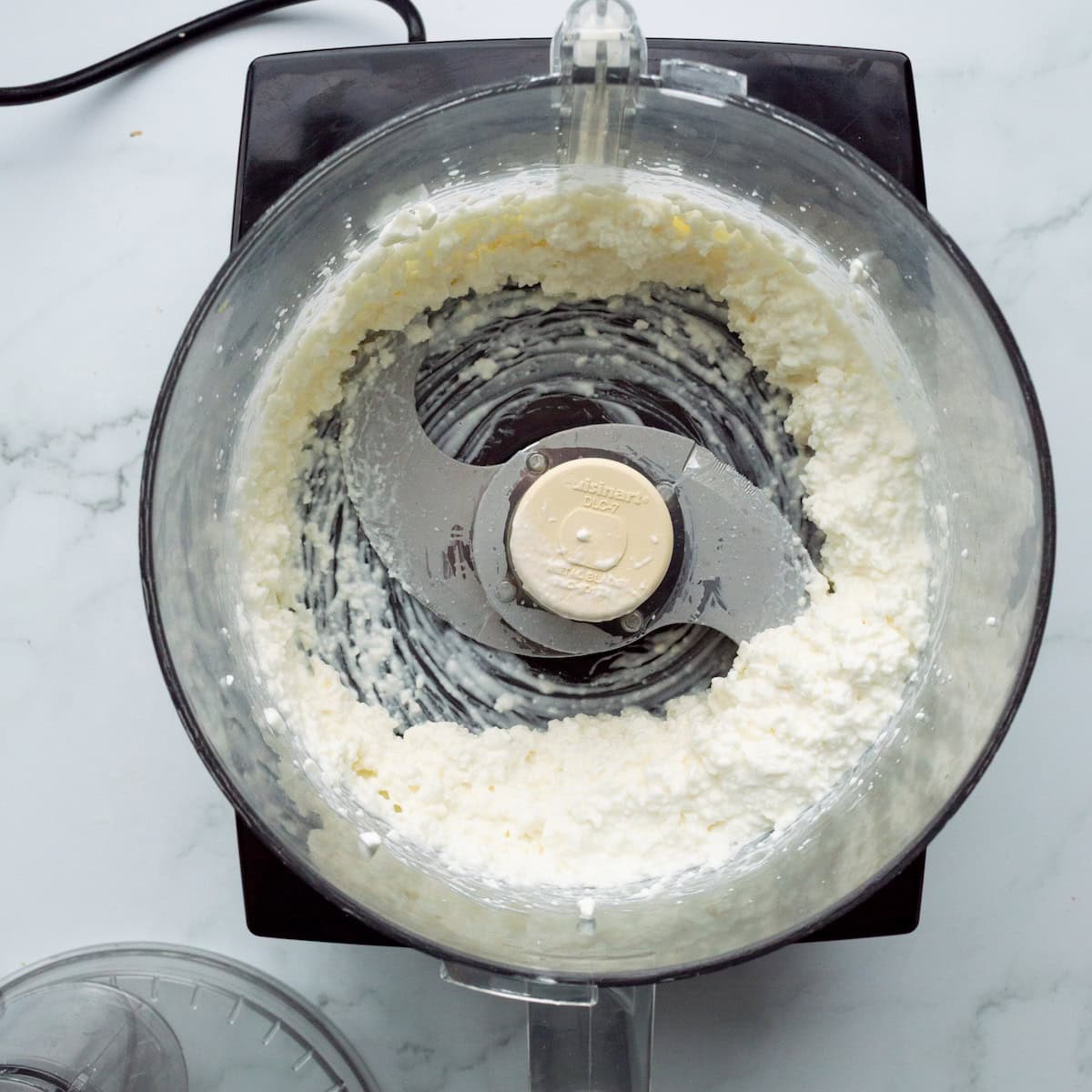 Pulsing cottage cheese in a food processor until smooth.