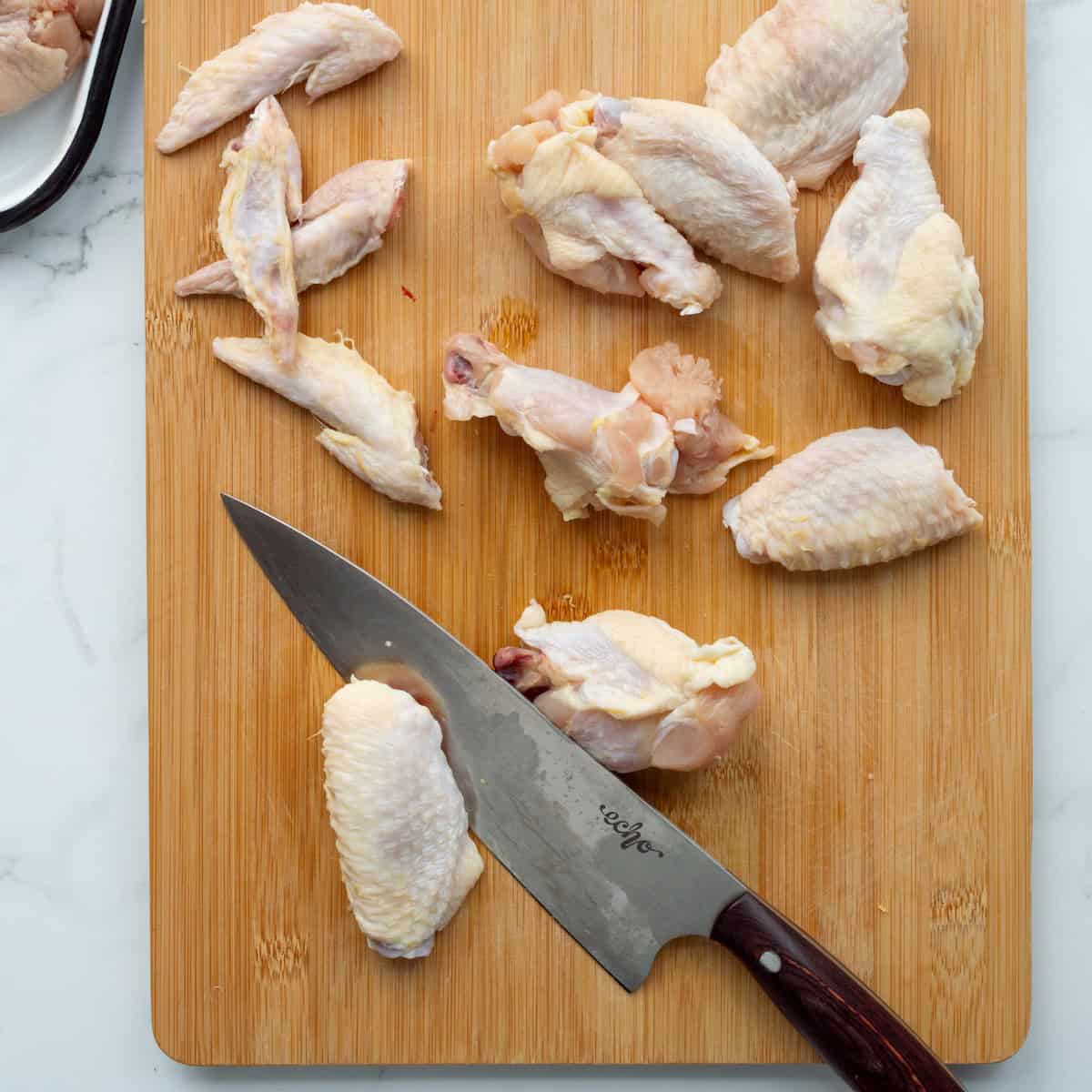 Cutting the wing tips from chicken wings and dividing the wings into flats and drumettes.