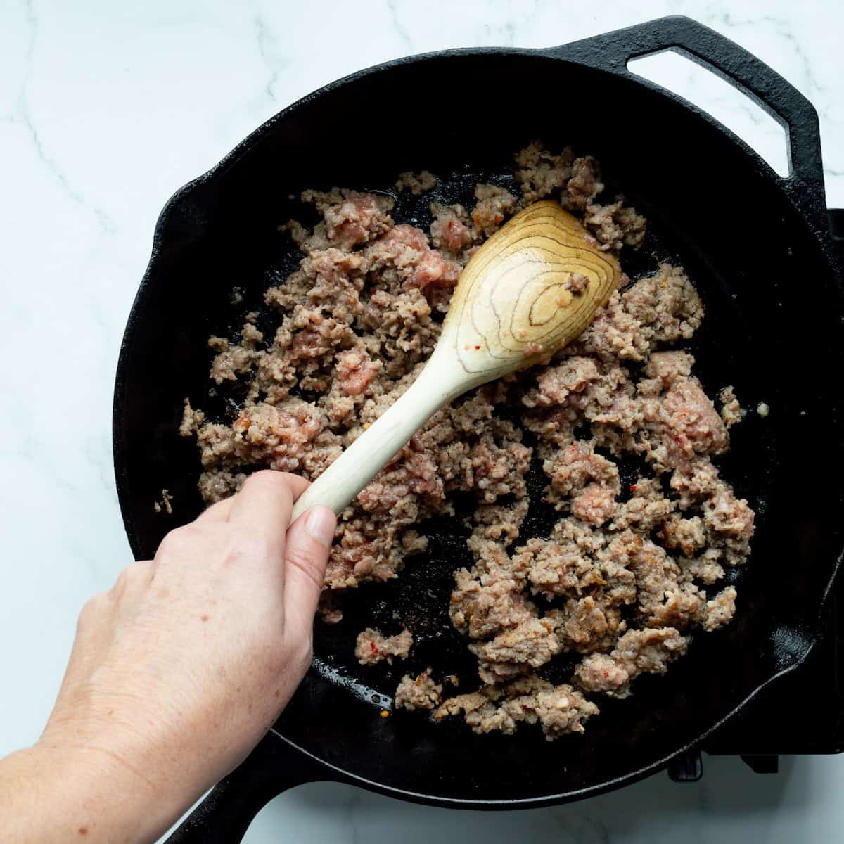 Browning breakfast sausage in a cast iron skillet.