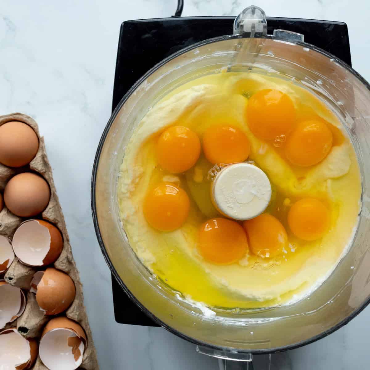 Blended cottage cheese in a food processor with whole eggs on top.