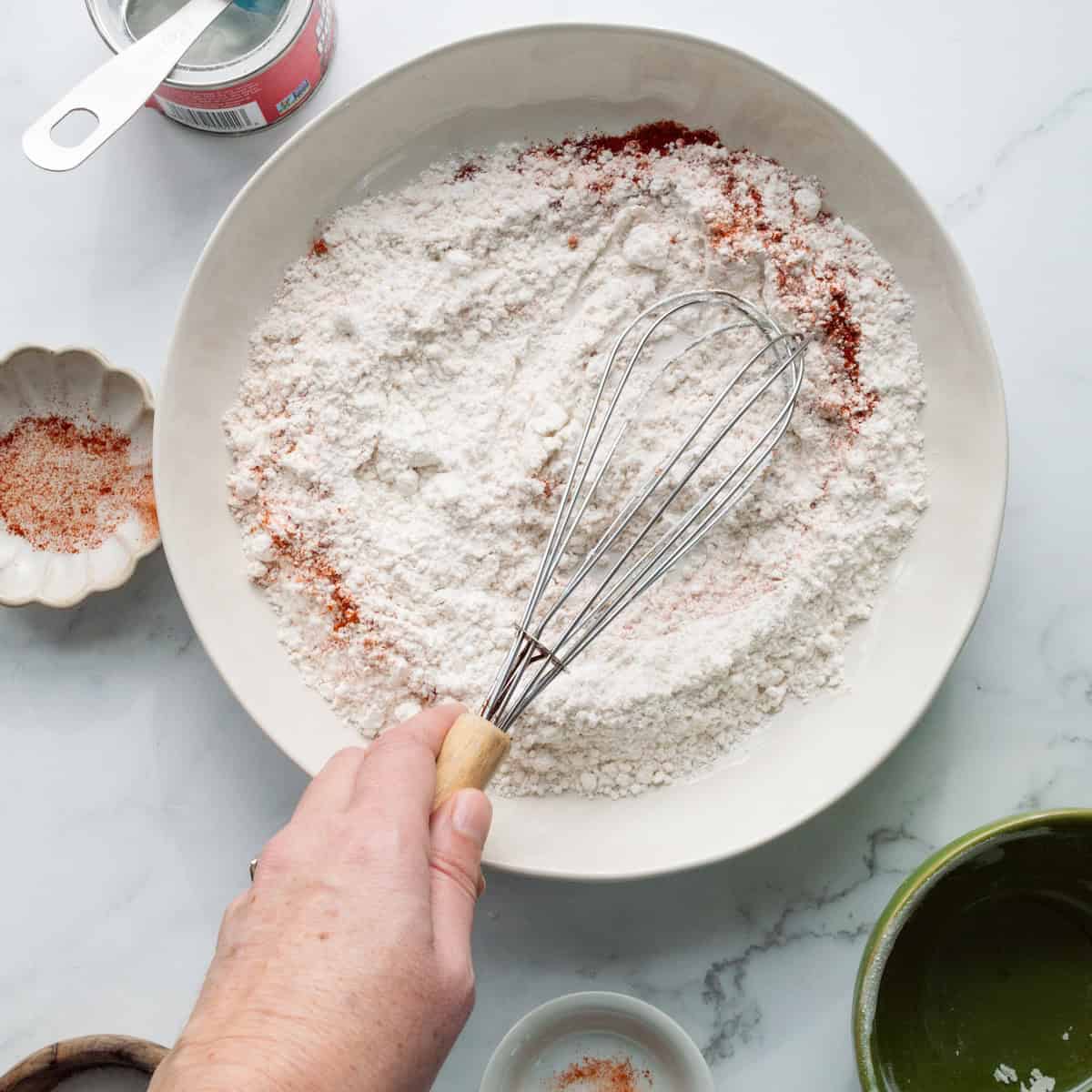 Whisking all purpose flour, paprika, cayenne pepper, salt, and baking powder in a large white bowl.