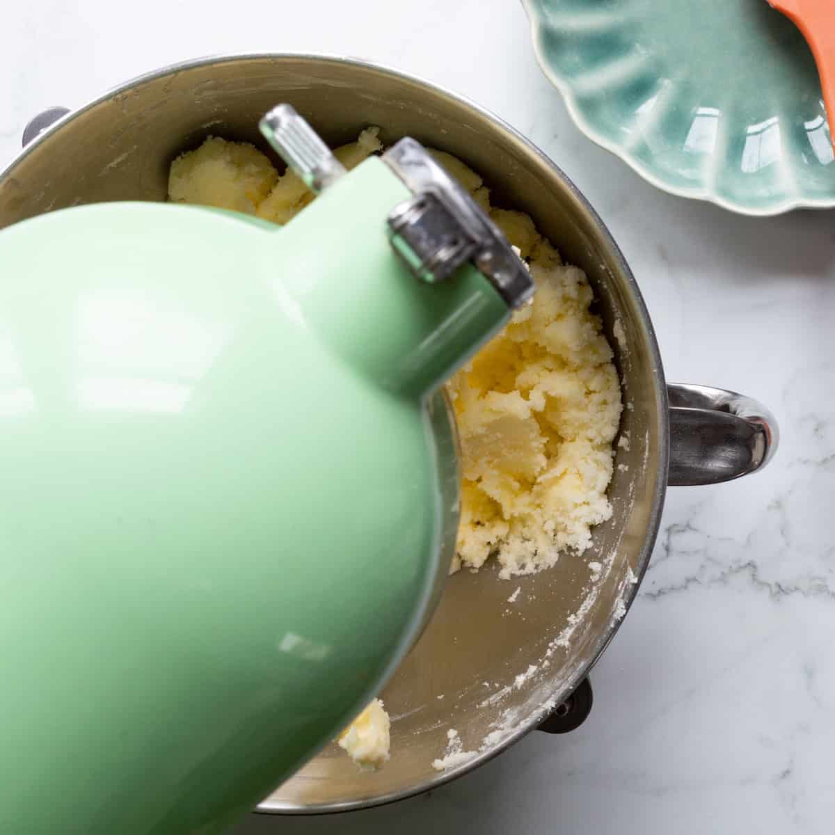 Creaming butter and sugar in a light green heavy duty mixer.
