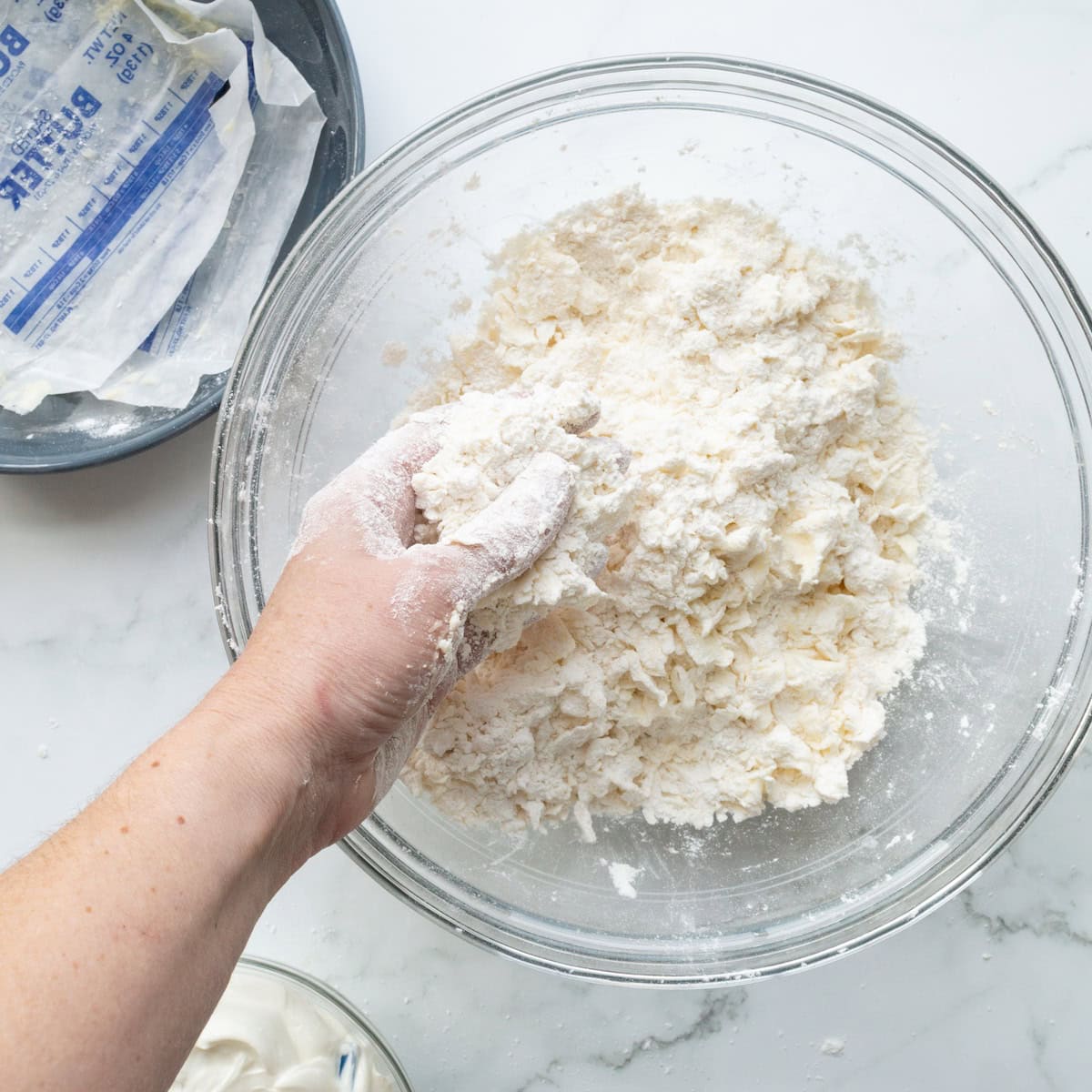 Mixing softened butter with self rising flour in a large glass bowl.