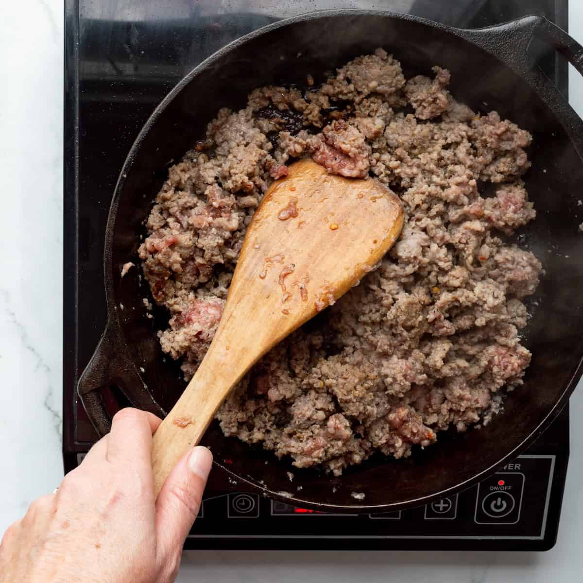 Browning sausage in a cast-iron skillet.