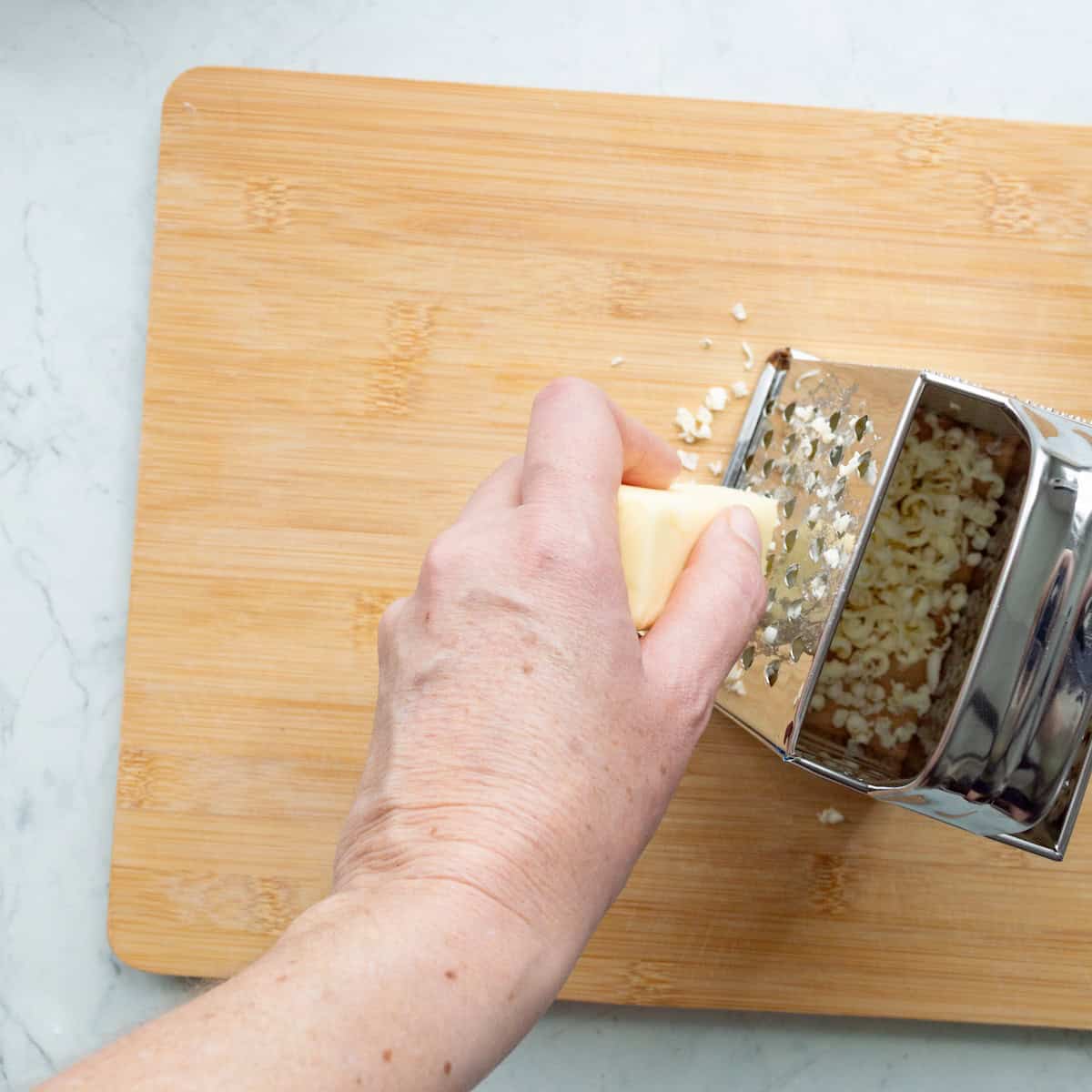 Grating frozen butter on a box grater.