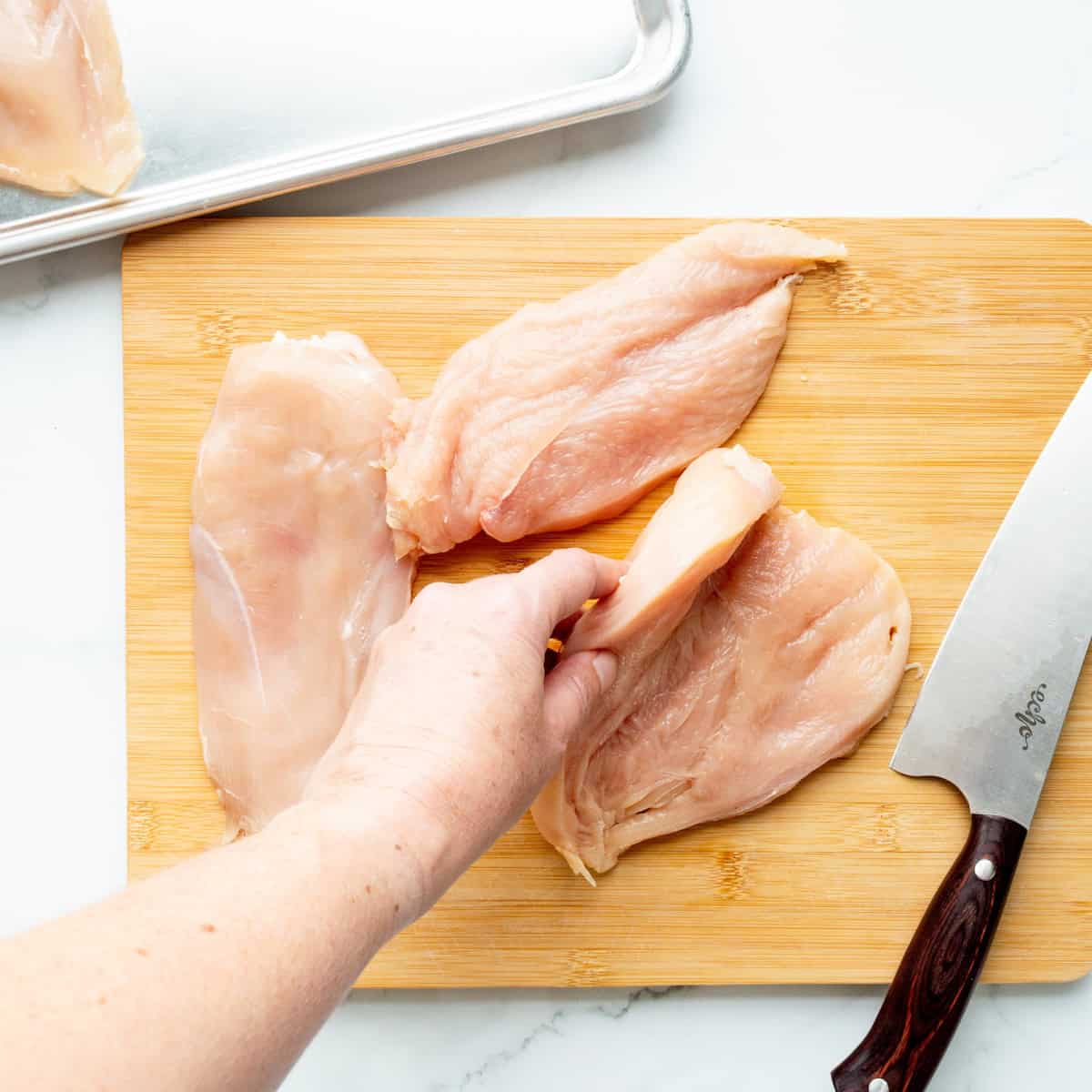Cutting boneless skinless chicken breasts into cutlets.
