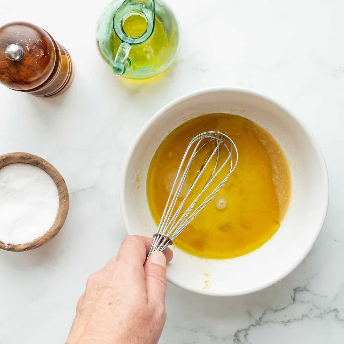 Whisking together a vinaigrette in a white bowl.