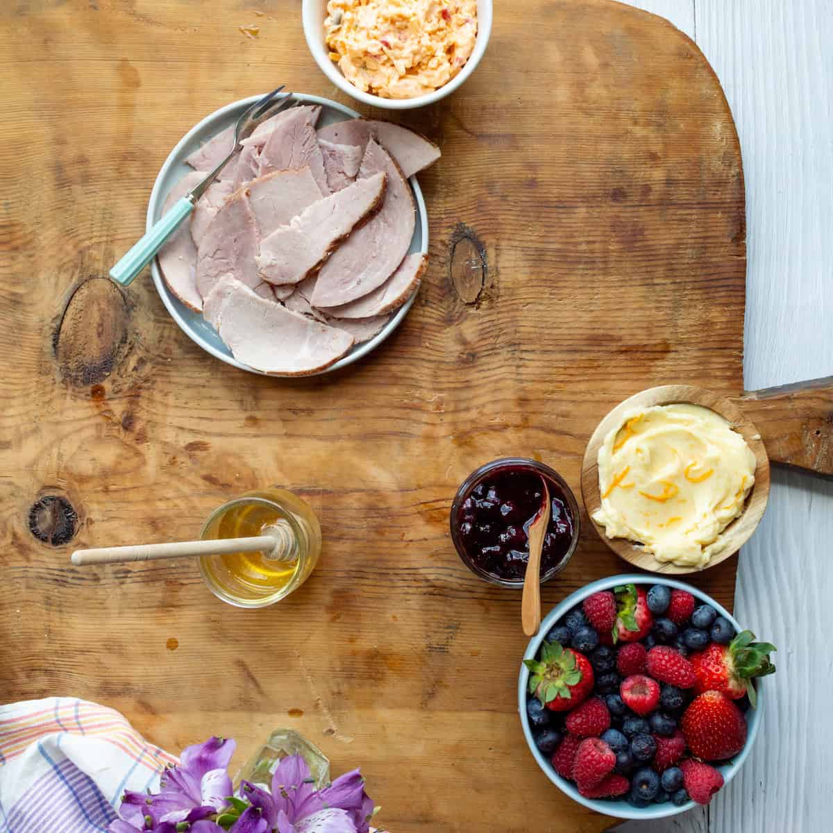 A large wooden board topped with toppings and spreads for buttermilk biscuits.
