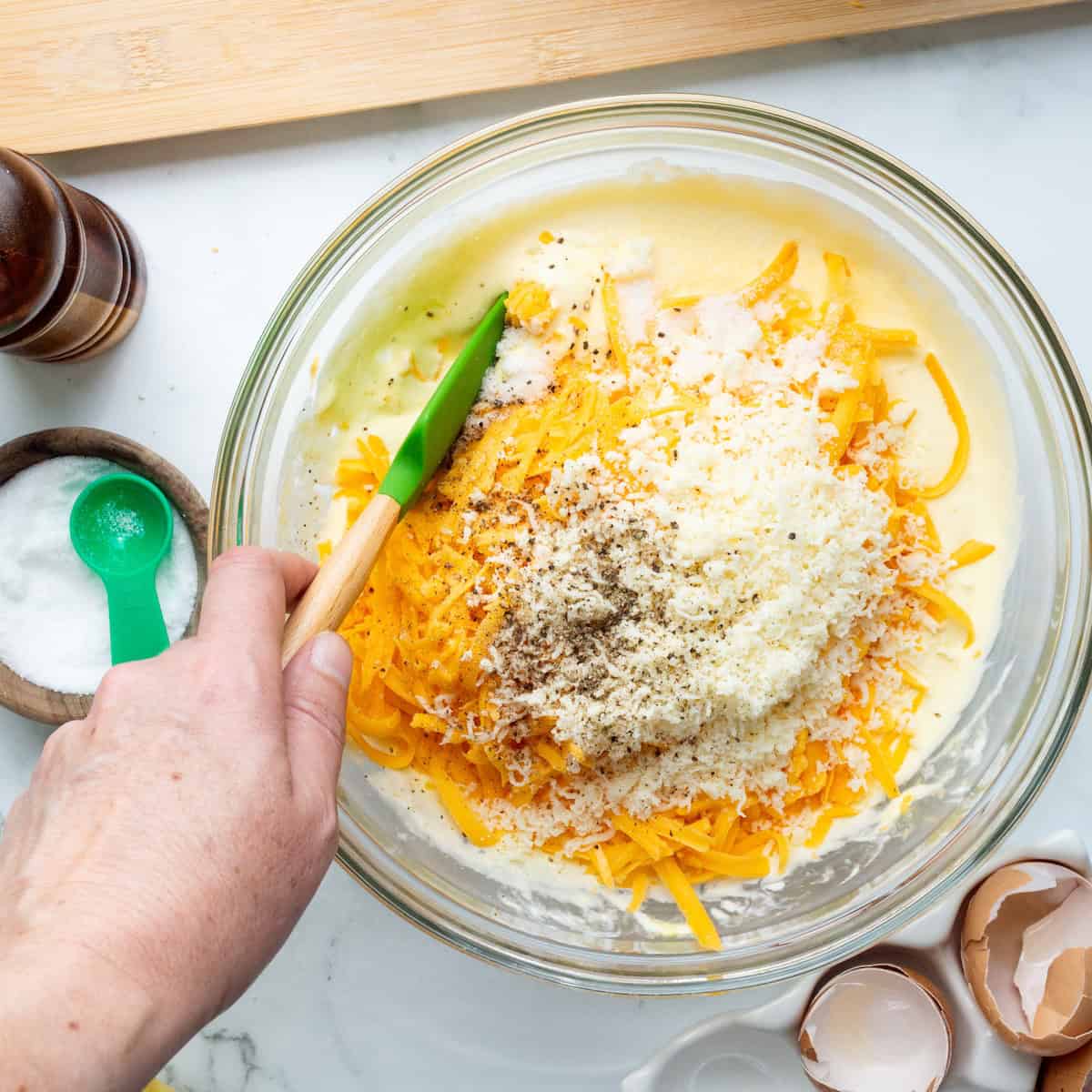 Mixing together the filling for squash casserole in a glass bowl.