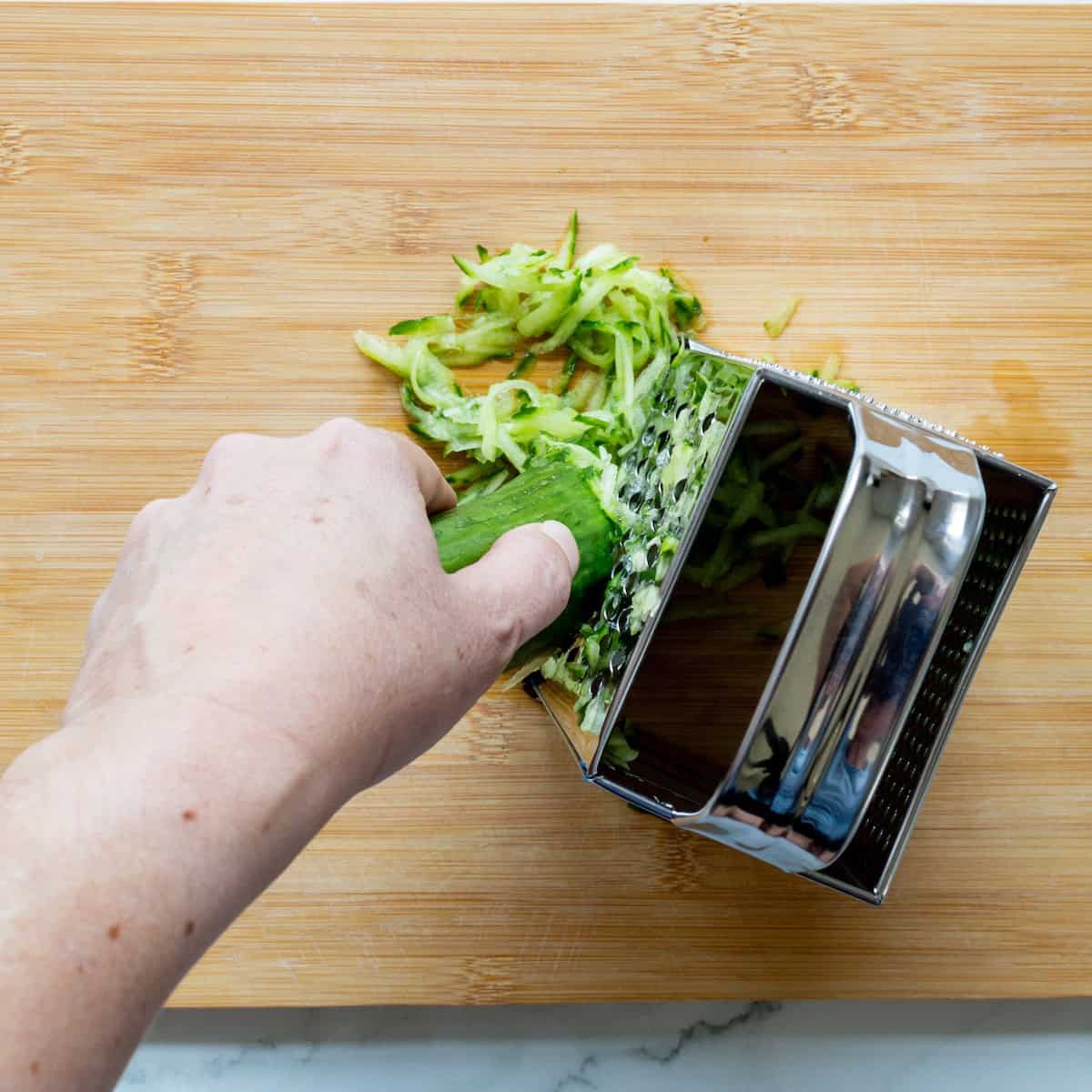 Grating cucumber using a box grater.