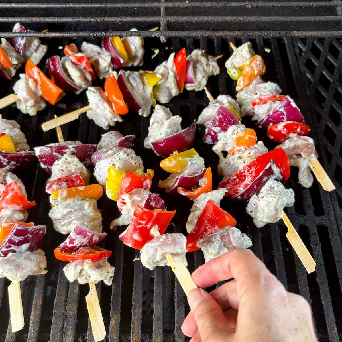 Placing chicken and vegetable kabobs on the grill.
