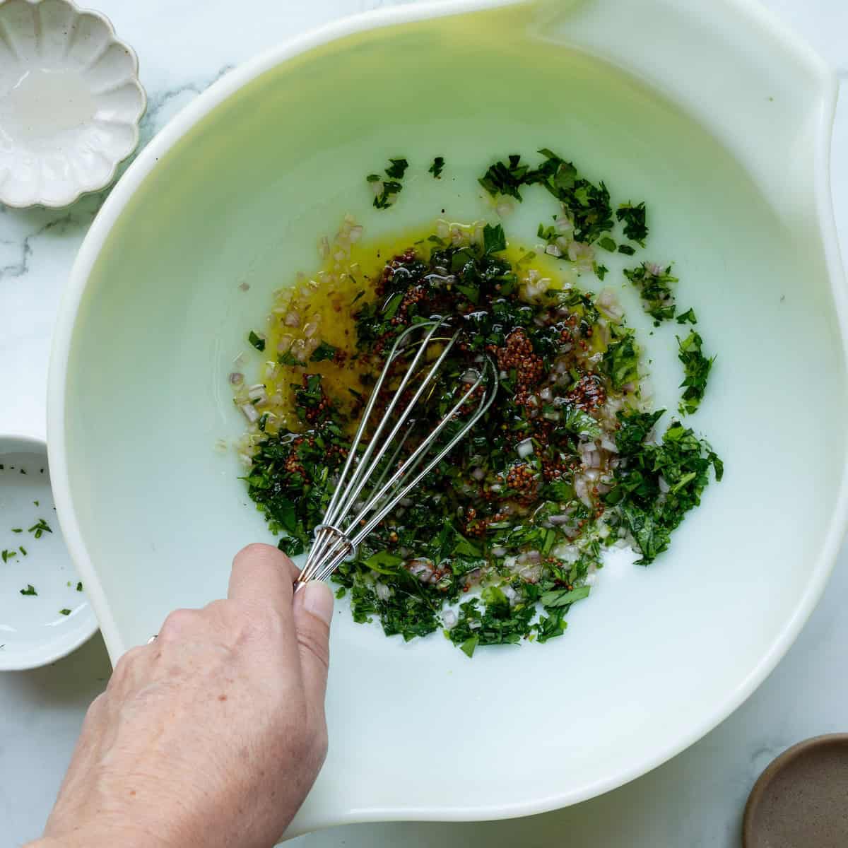 Whisking mustard vinaigrette in a large bowl.