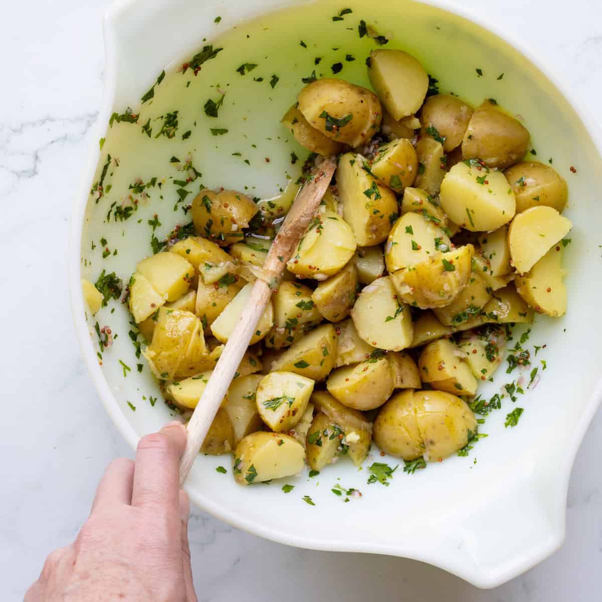 Stirring warm potato chunks in mustard vinaigrette.