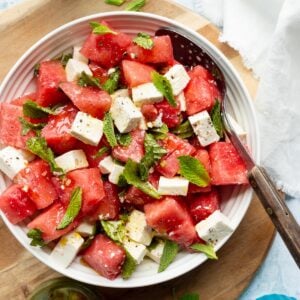 Watermelon, mint and feta salad with honey vinaigrette on a wooden board.