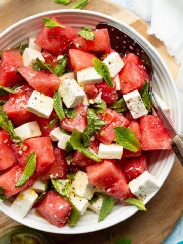 Watermelon, mint and feta salad with honey vinaigrette on a wooden board.