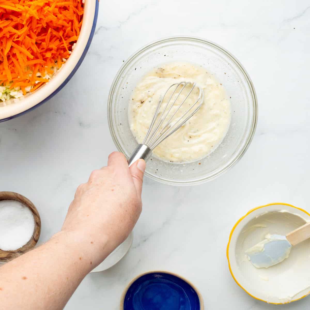 Whisking together the homemade slaw dressing in a glass bowl.
