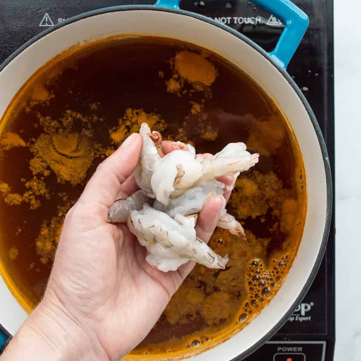 Adding shrimp to a pot of Old Bay seasoned boiling water.