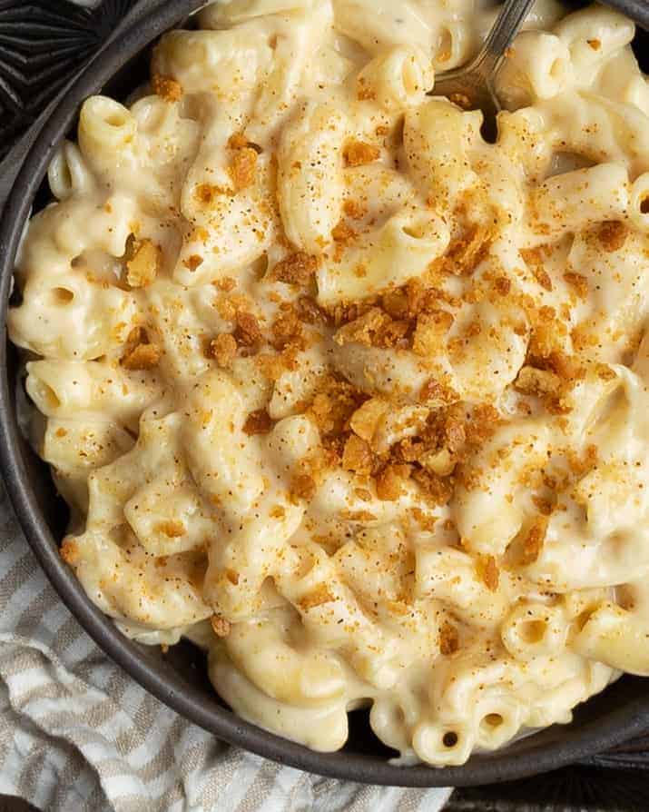 Delicious creamy mac and cheese with breadcrumb topping in a black bowl.