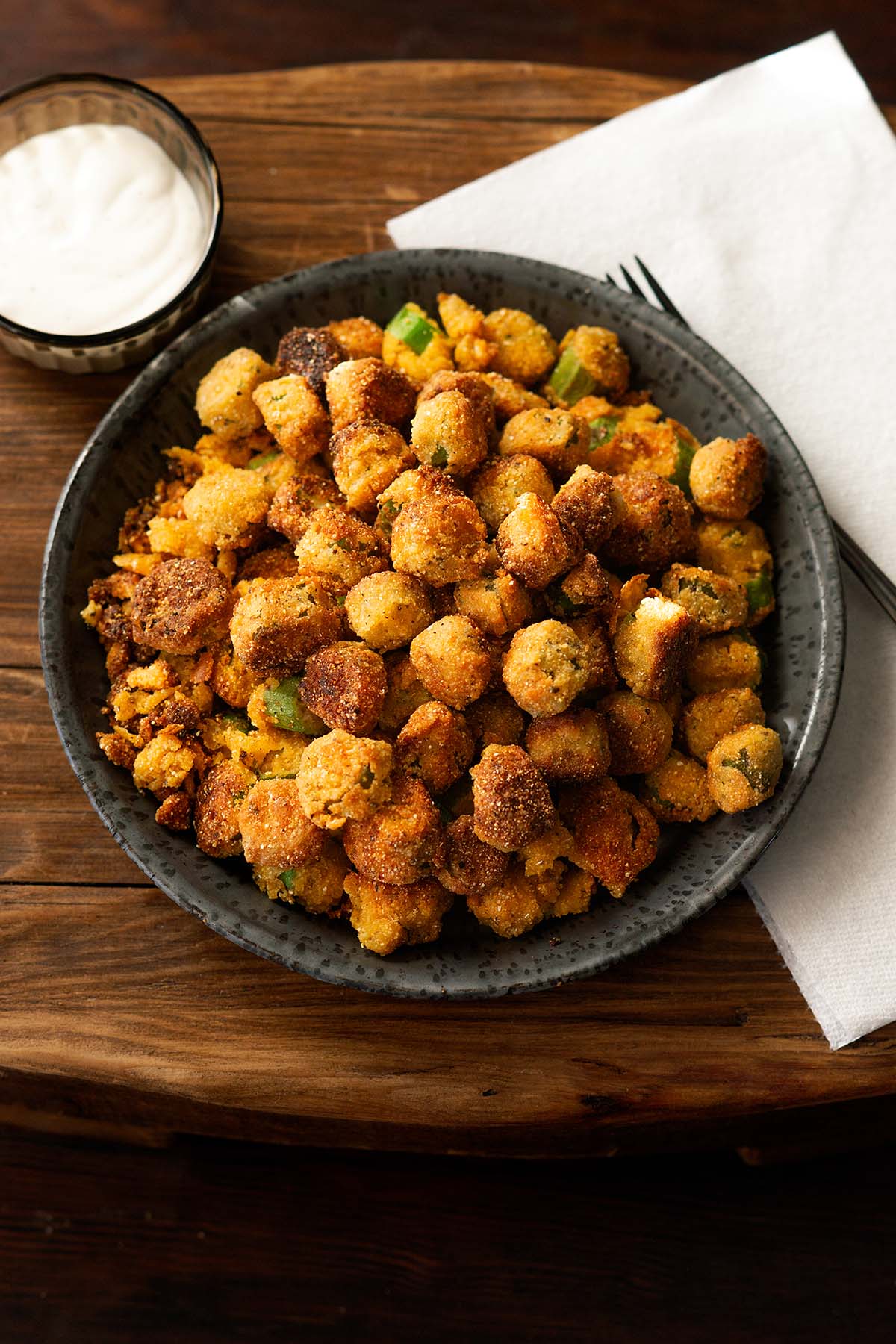 Crispy Southern fried okra served in a black bowl with a side of dipping sauce.