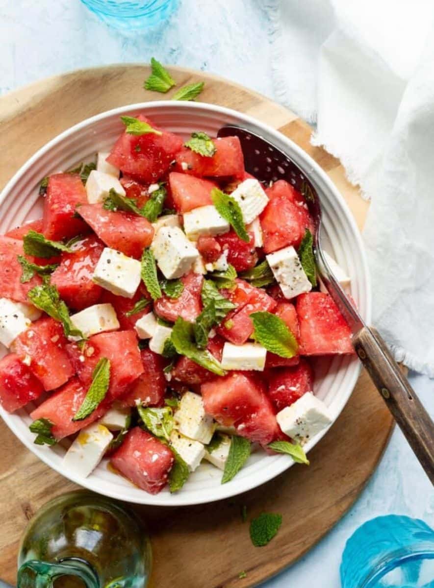 A bowl of watermelon feta and mint salad served with a large spoon for a refreshing summer side dish.