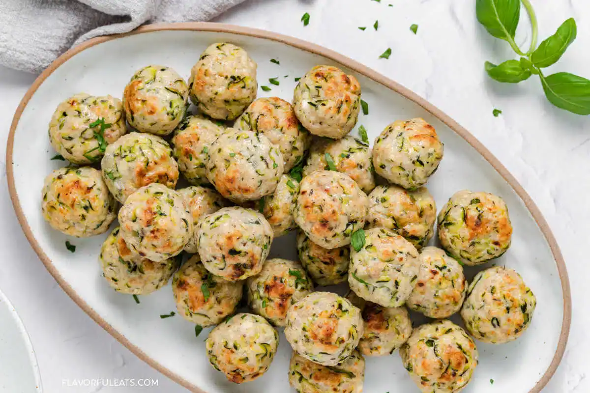 Turkey, zucchini, and feta meatballs arranged on a serving platter with lightly browned edges and chopped herbs.