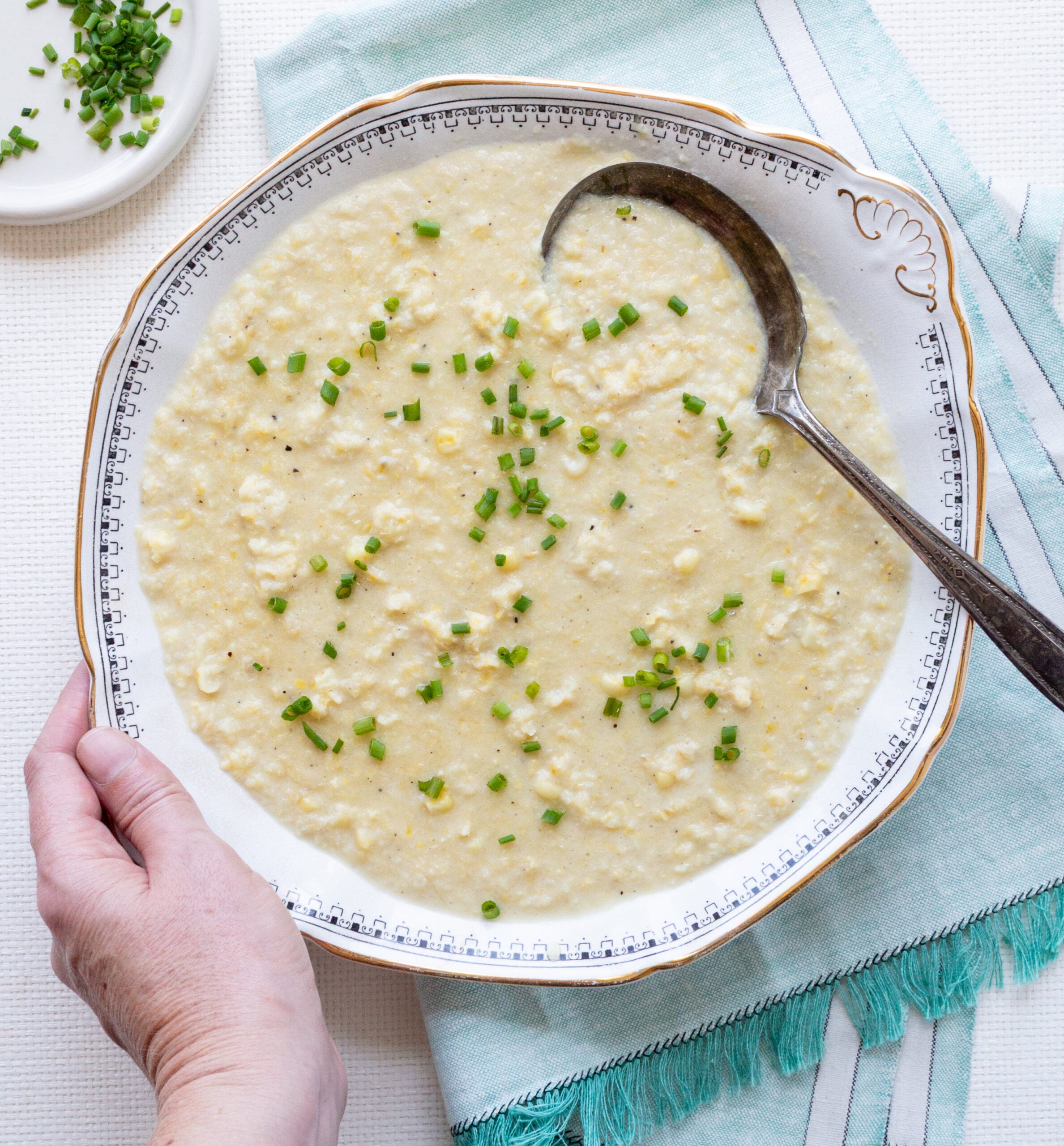 Placing an antique bowl filled with Southern-style creamed corn on an aqua linen.