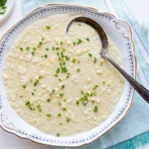 An antique bowl filled with Southern-style creamed corn on an aqua linen.