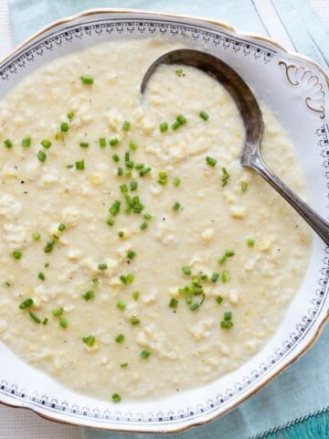 An antique bowl filled with Southern-style creamed corn on an aqua linen.