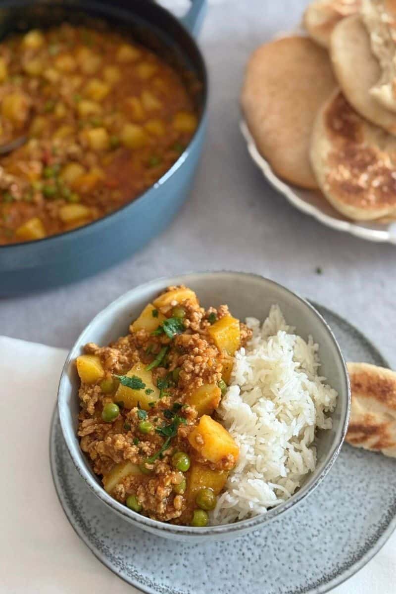Thai coconut turkey potato curry served with white rice, potatoes, peas, and chopped herbs.