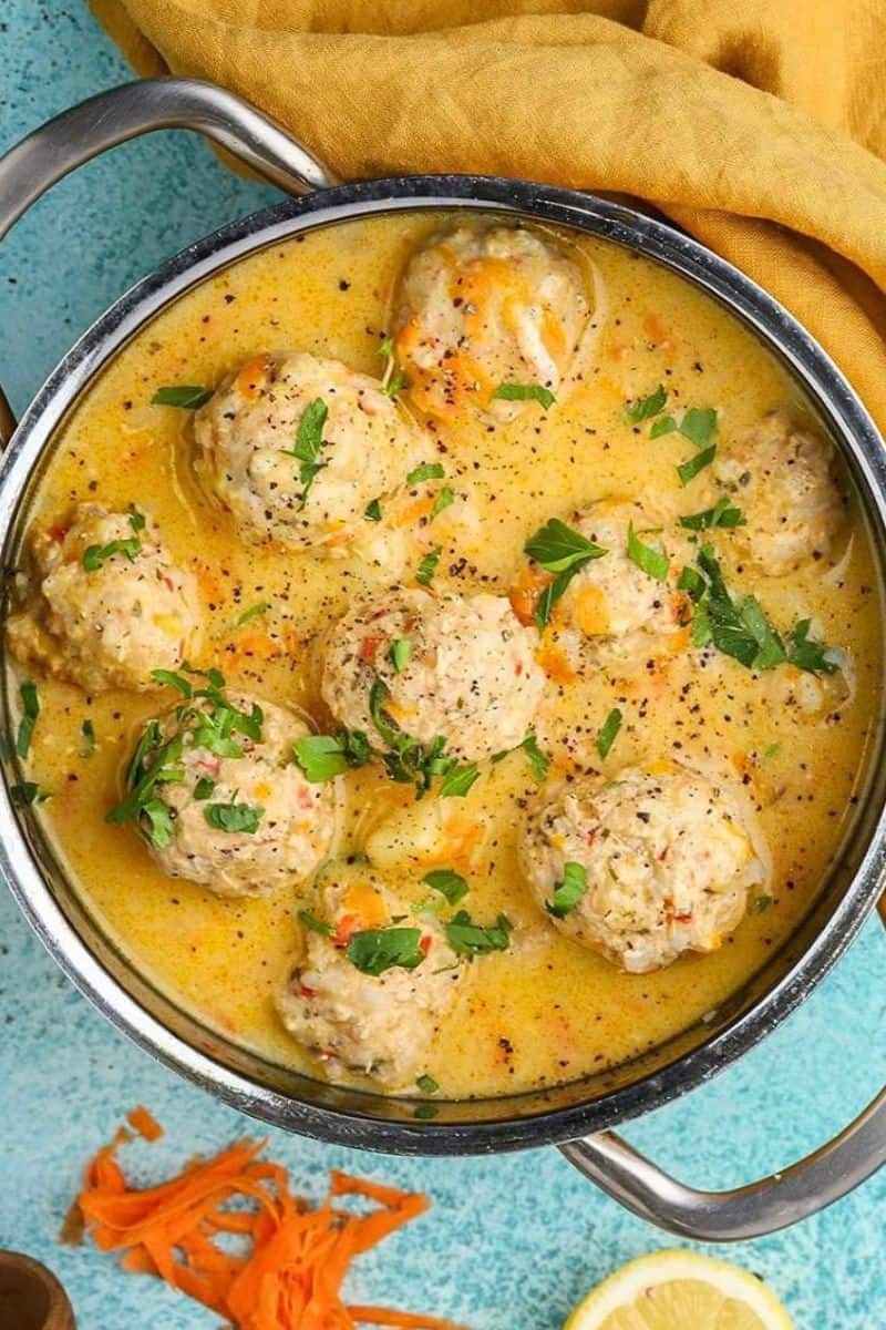Greek meatball soup with tender meatballs in a creamy broth, topped with chopped herbs and black pepper.