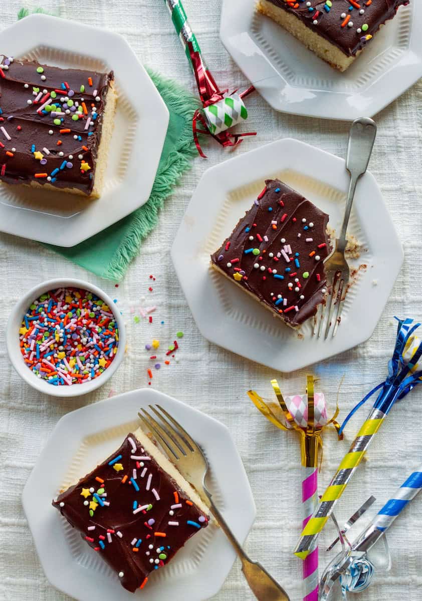 Small plates topped with squares of yellow cake with chocolate fudge frosting.