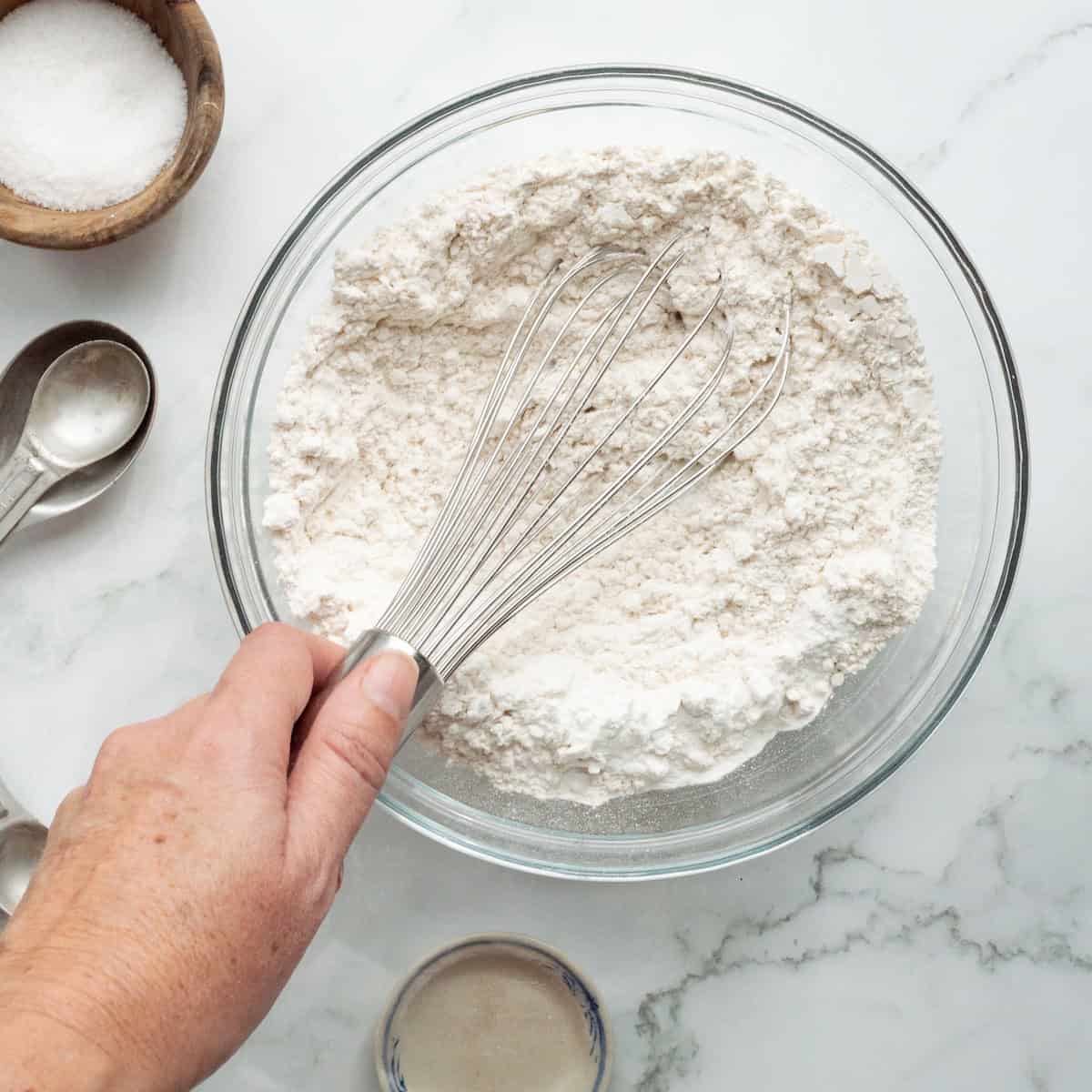 Whisking together the dry ingredients for yellow cake in a clear bowl.