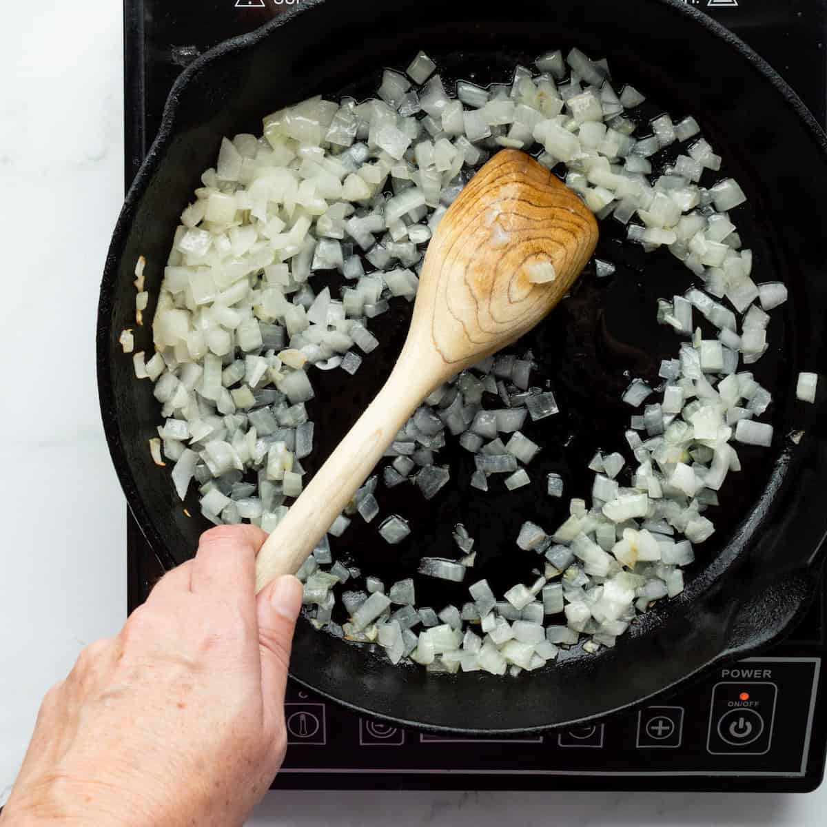Sauteing onion in a cast-iron skillet.