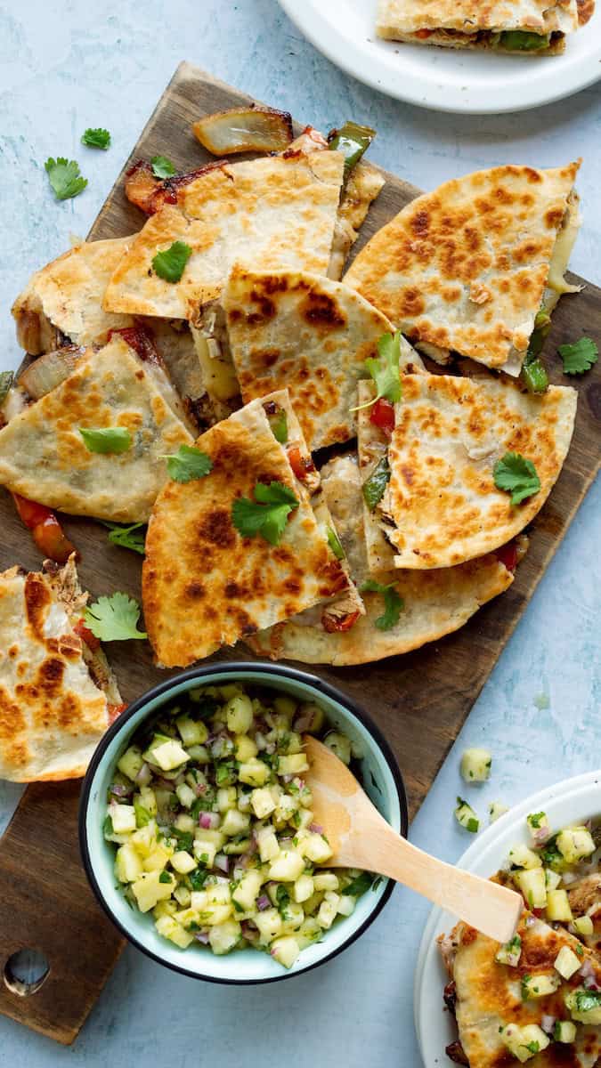 Jerk chicken quesadilla recipe with crispy golden tortillas, colorful peppers, and melted cheese, served with fresh pineapple salsa and cilantro.