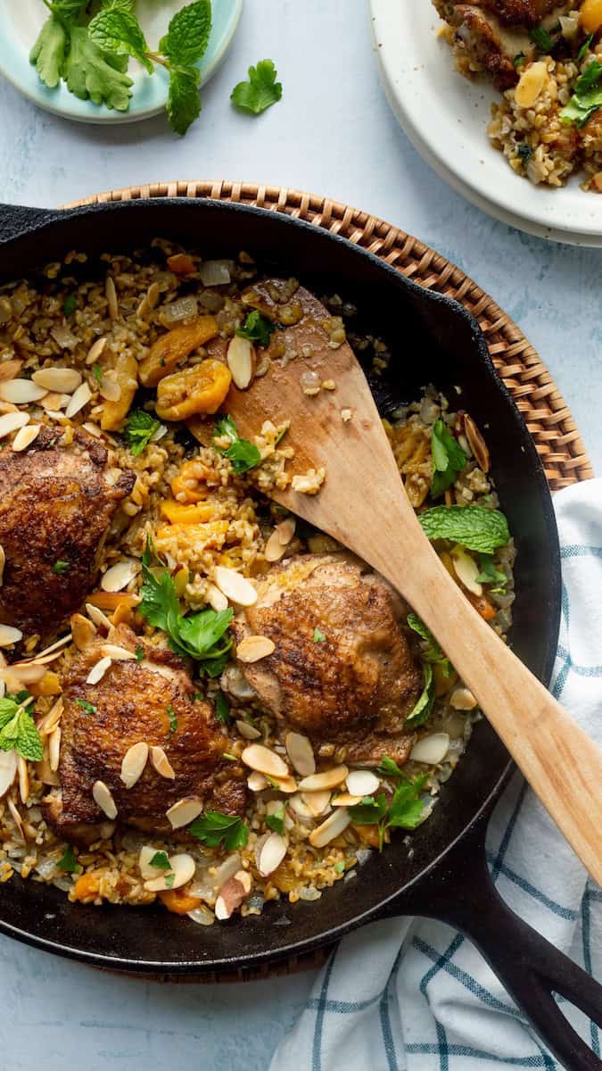 Freekeh recipe with chicken and apricots cooked in a skillet with onions, toasted almonds, and fresh herbs for a hearty one-pan meal.