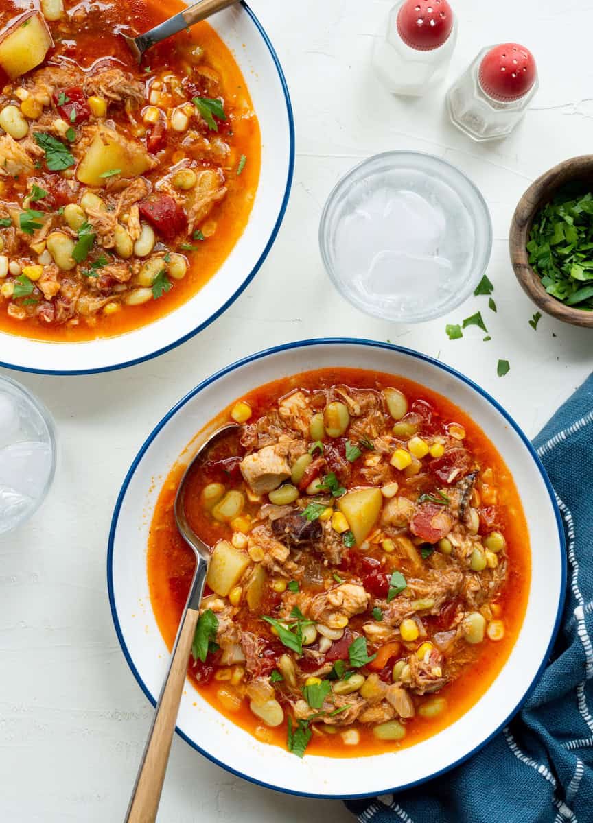Easy Brunswick stew recipe with shredded chicken, potatoes, corn, lima beans, and tomatoes in a rich broth, topped with fresh parsley.